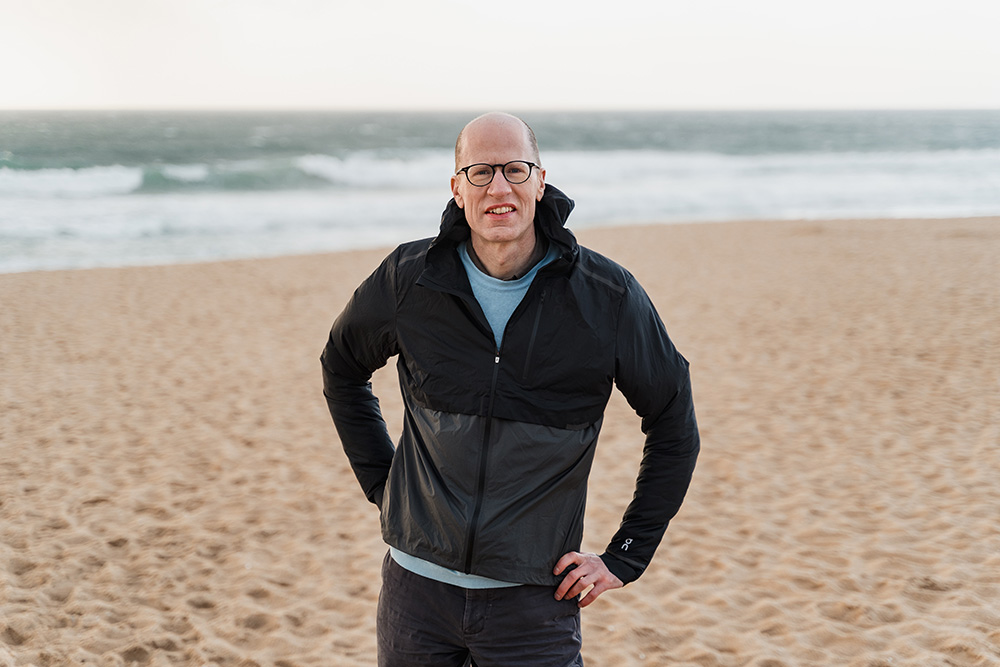 Outdoors portrait of Nick Bostrom in a black jacket at a beach
