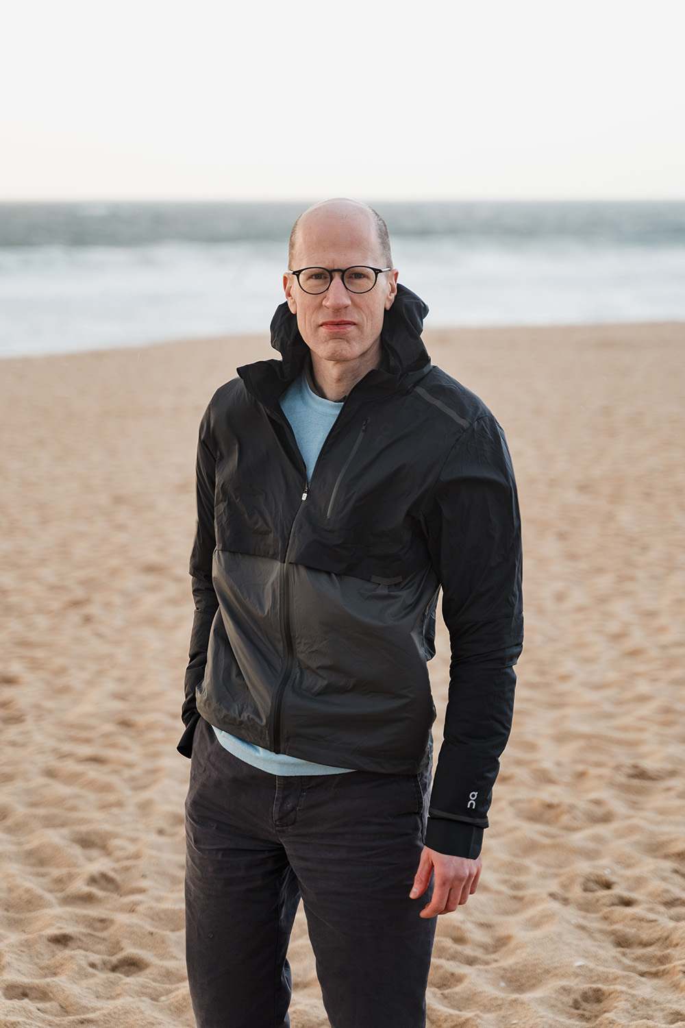 Outdoors portrait of Nick Bostrom in a black jacket at a beach