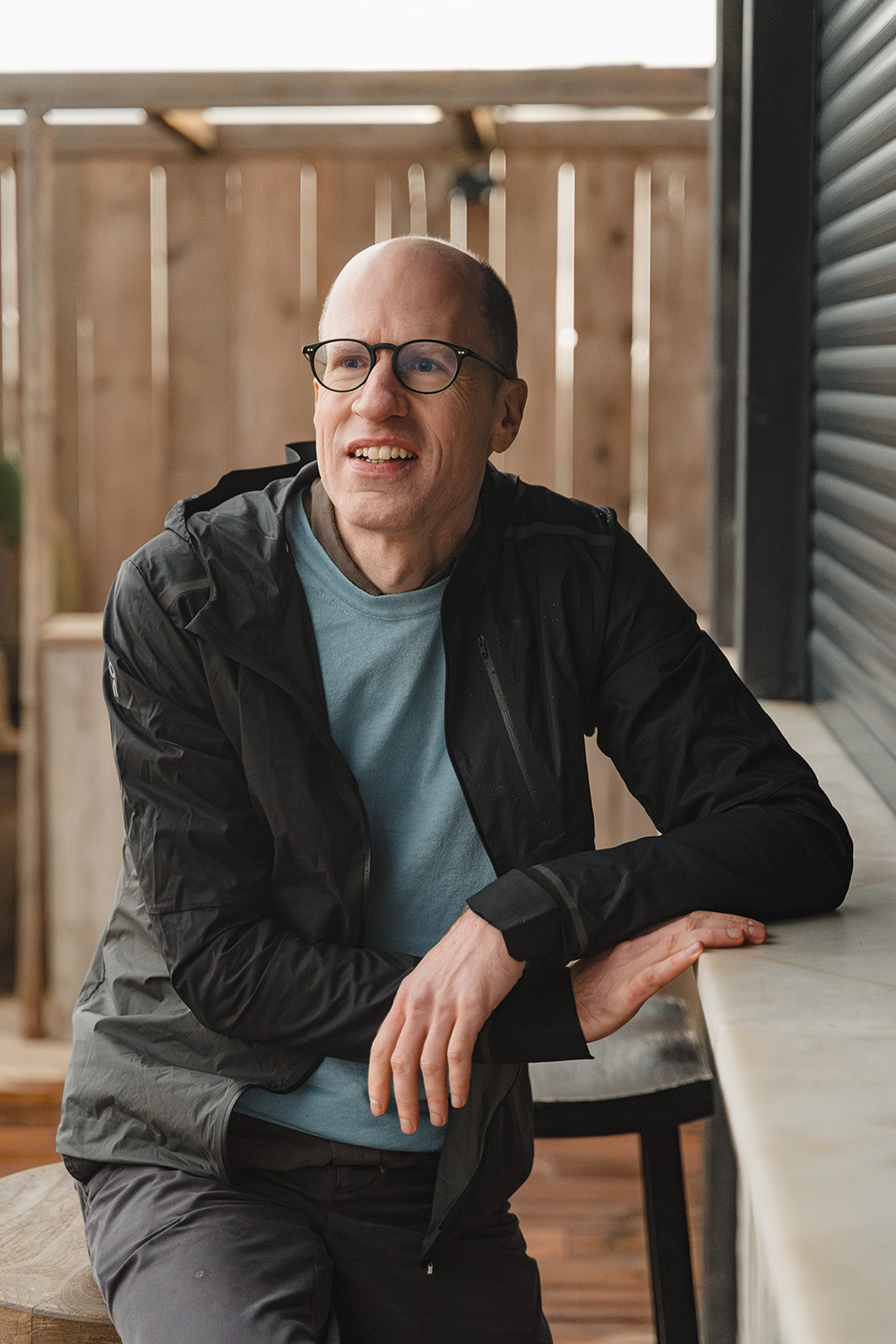 Portrait of Nick Bostrom in a black jacket at an outdoors beach house